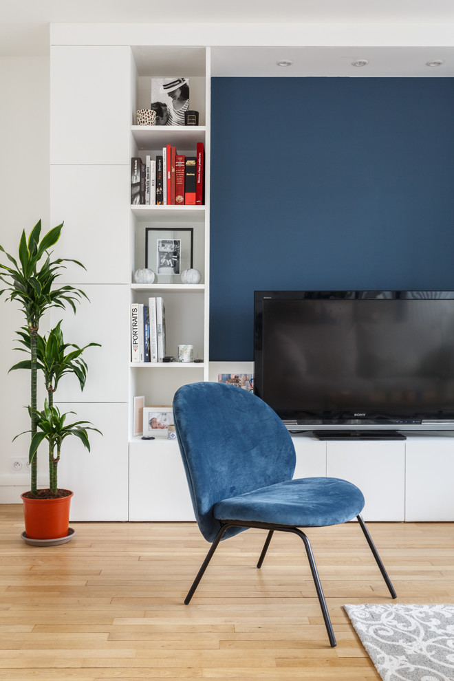 Foto på ett mellanstort funkis allrum med öppen planlösning, med ett finrum, blå väggar, ljust trägolv, en fristående TV och beiget golv