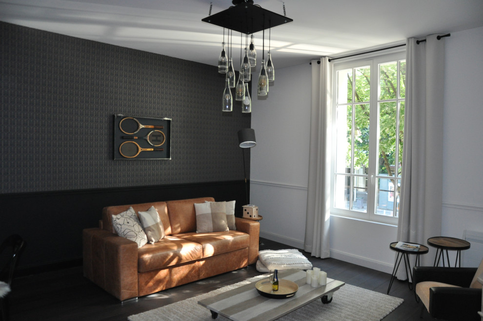 Kleines, Offenes Industrial Wohnzimmer mit schwarzer Wandfarbe, dunklem Holzboden, Kamin, Kaminumrandung aus Stein, TV-Wand und braunem Boden in Reims