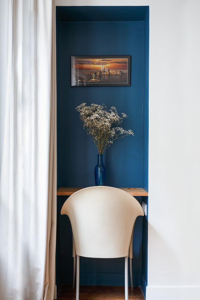 Idée de décoration pour un salon minimaliste de taille moyenne et ouvert avec un mur bleu, un sol en bois brun, une cheminée standard, un manteau de cheminée en pierre, un téléviseur indépendant et un sol marron.