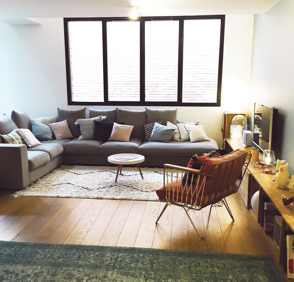 Diseño de salón abierto bohemio de tamaño medio sin chimenea con paredes blancas, suelo de madera clara, televisor independiente y suelo marrón