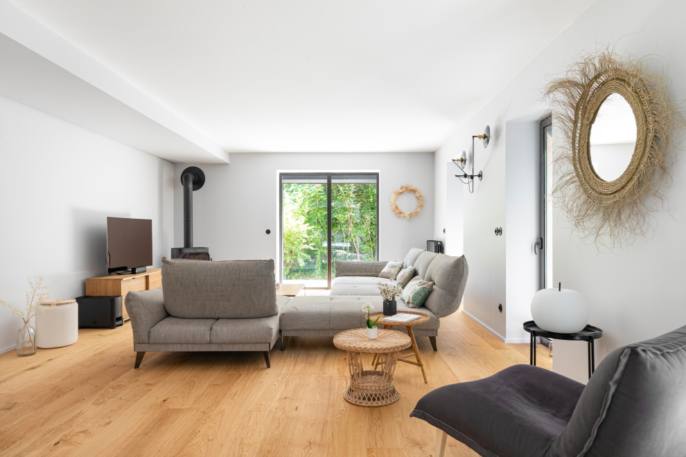 Großes, Offenes Eklektisches Wohnzimmer mit beiger Wandfarbe, hellem Holzboden, Kaminofen und freistehendem TV in Lyon