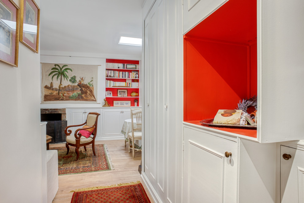 Inspiration för mellanstora eklektiska vardagsrum, med ett bibliotek, vita väggar, ljust trägolv, en standard öppen spis, en spiselkrans i tegelsten och brunt golv