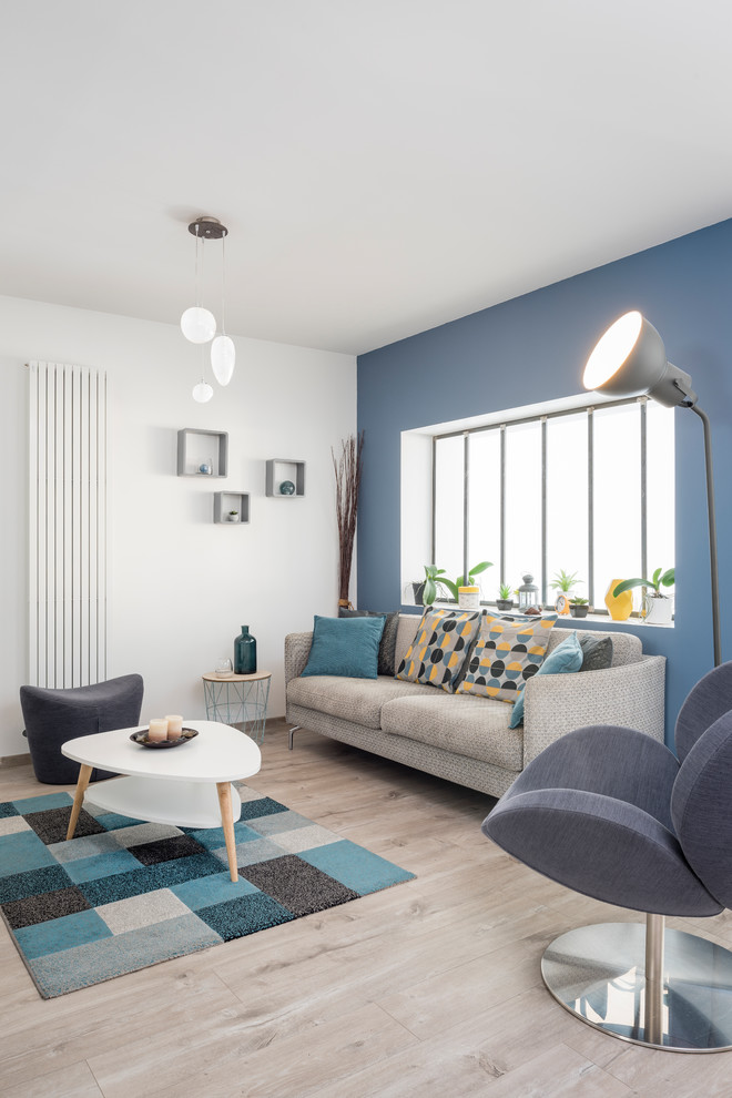 Inspiration pour un salon design avec un mur bleu, parquet clair, un sol beige et éclairage.