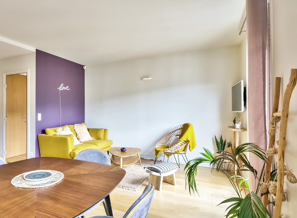 Cette photo montre un salon rétro de taille moyenne et ouvert avec un mur violet, un sol en bois brun, aucune cheminée, un téléviseur fixé au mur et un sol beige.