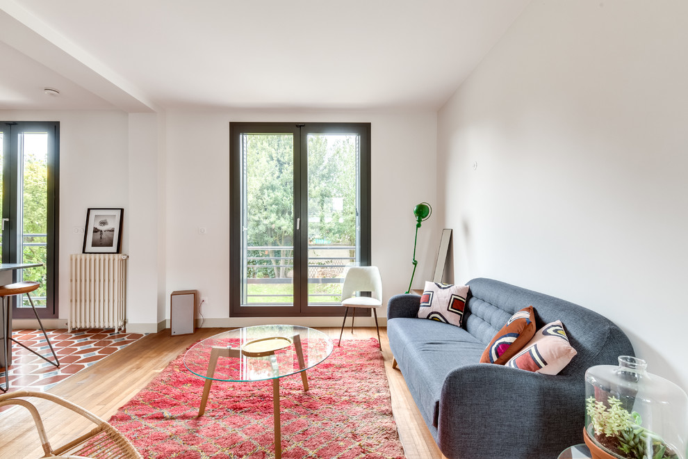 Abgetrenntes Mid-Century Wohnzimmer mit weißer Wandfarbe, hellem Holzboden und beigem Boden in Paris