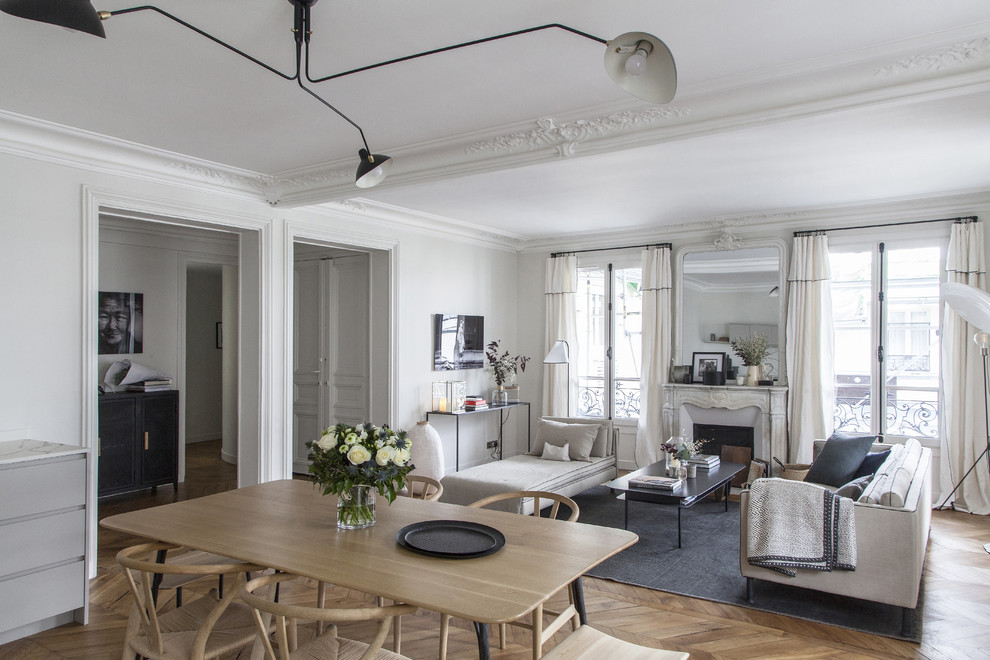 パリにある高級な中くらいな北欧スタイルのおしゃれなLDK (白い壁、淡色無垢フローリング、標準型暖炉、石材の暖炉まわり、壁掛け型テレビ、茶色い床) の写真