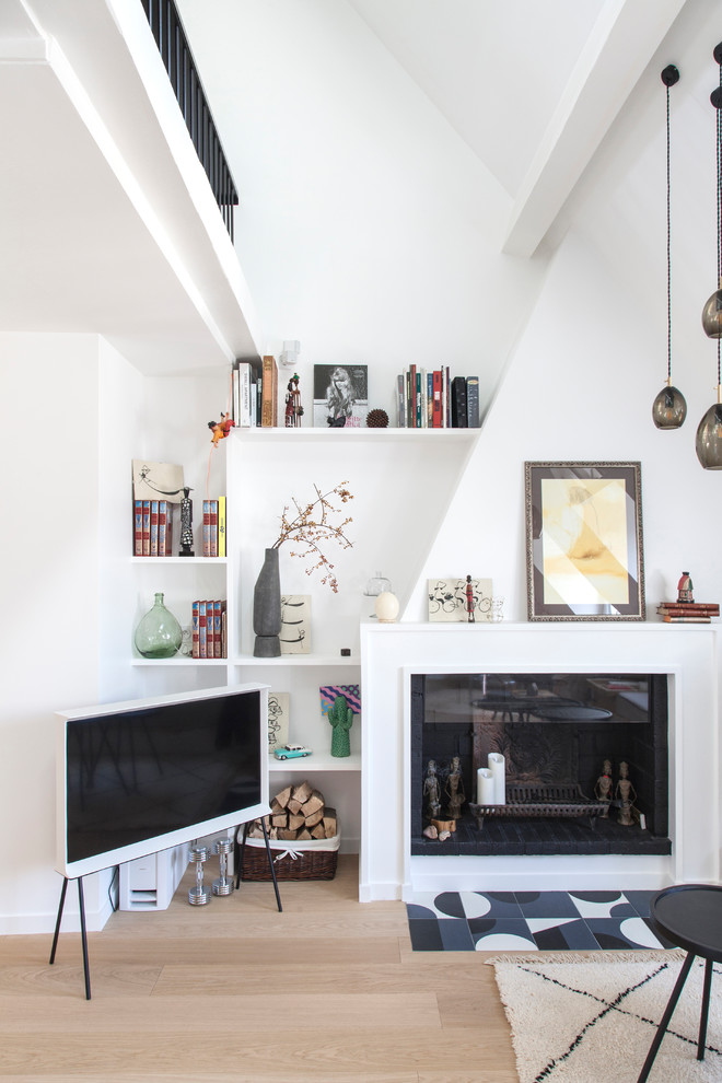 パリにある高級な中くらいなコンテンポラリースタイルのおしゃれなリビングロフト (ライブラリー、白い壁、淡色無垢フローリング、標準型暖炉、木材の暖炉まわり、据え置き型テレビ、ベージュの床) の写真