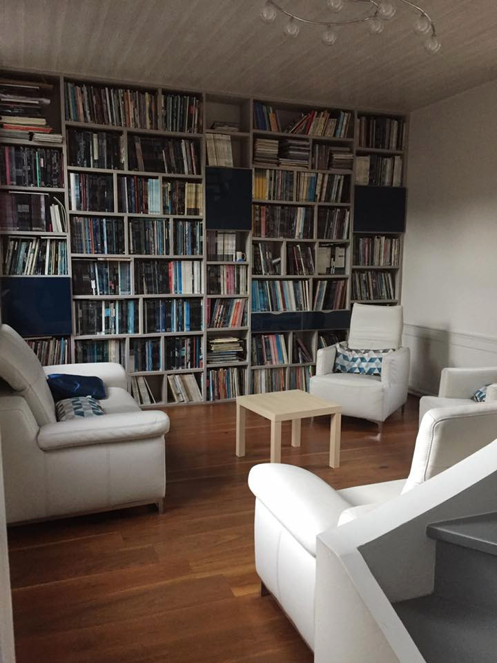 Ejemplo de biblioteca en casa abierta tradicional renovada de tamaño medio sin chimenea con paredes beige, suelo de madera oscura y suelo marrón