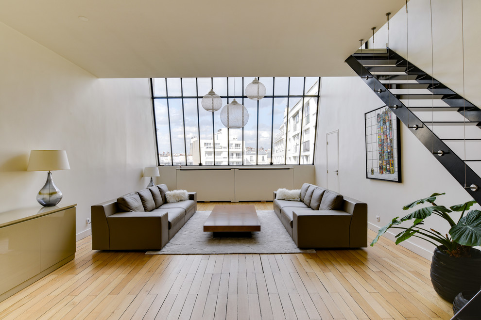 Aménagement d'un grand salon contemporain ouvert avec une salle de réception, un mur blanc, parquet clair, un sol beige et éclairage.