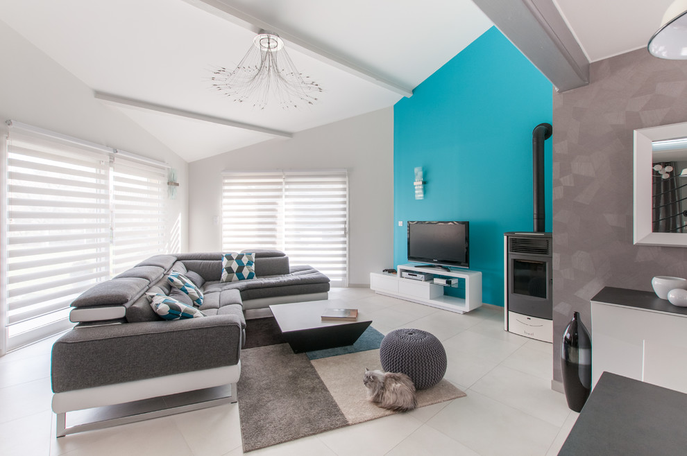 Свежая идея для дизайна: большая открытая гостиная комната в современном стиле с синими стенами, полом из керамической плитки, печью-буржуйкой, отдельно стоящим телевизором и серым полом - отличное фото интерьера