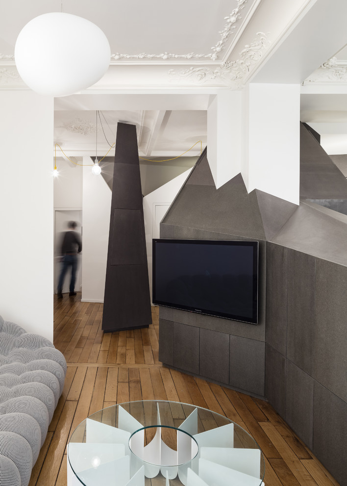 Small contemporary open plan living room in Paris with medium hardwood flooring, a wall mounted tv, black walls and no fireplace.