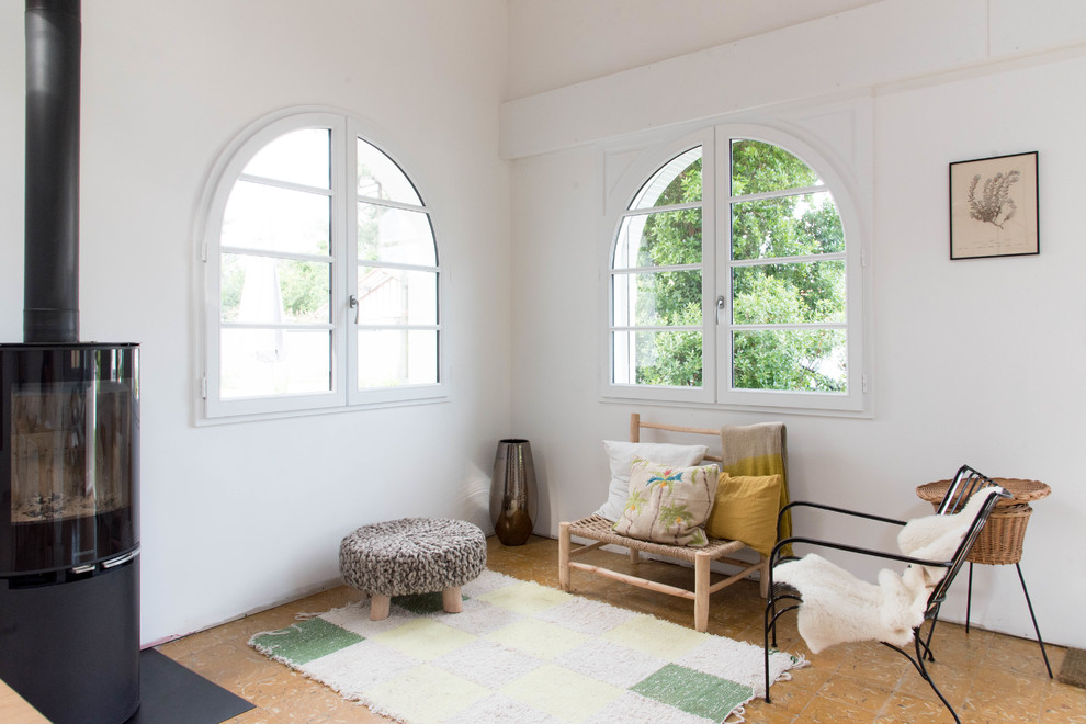 Ispirazione per un soggiorno minimalista con pareti bianche, pavimento in sughero, stufa a legna e cornice del camino in metallo