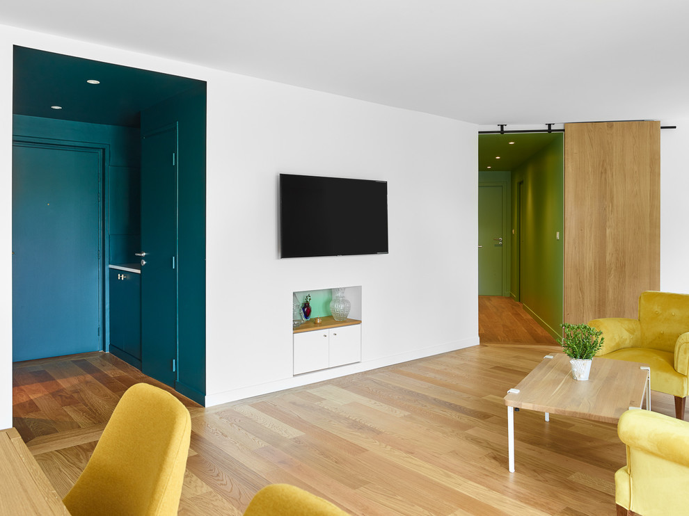 Foto de salón abierto contemporáneo grande con paredes blancas, suelo de madera clara y televisor colgado en la pared