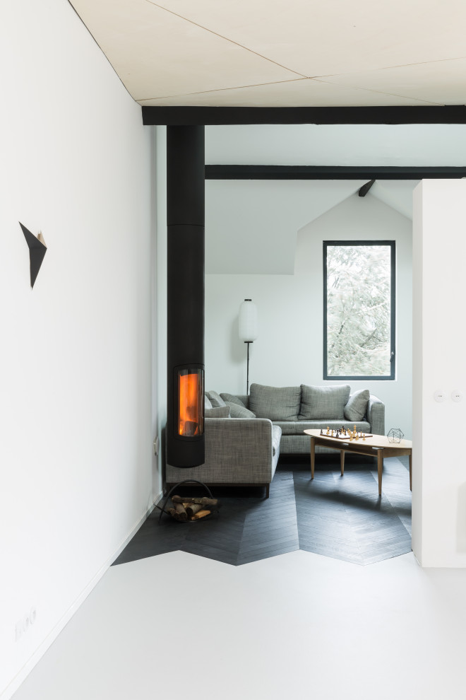 На фото: открытая гостиная комната среднего размера в современном стиле с белыми стенами, деревянным полом, подвесным камином, фасадом камина из металла и черным полом с
