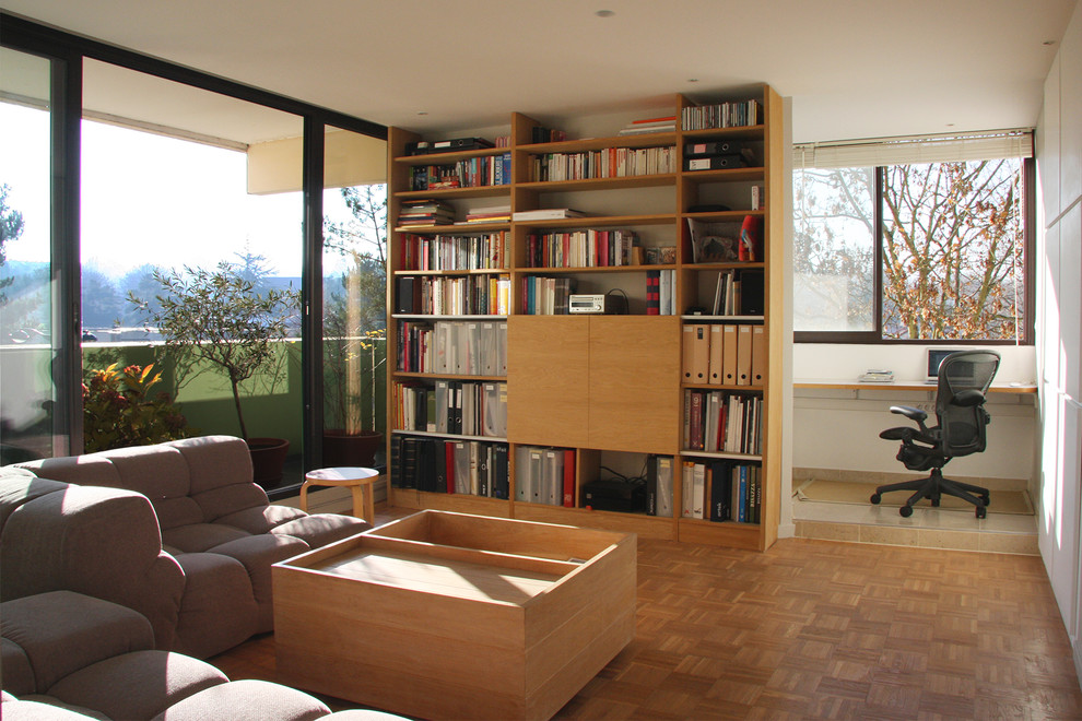 Esempio di un soggiorno design di medie dimensioni e aperto con libreria, pareti bianche, parquet chiaro, nessun camino e TV nascosta