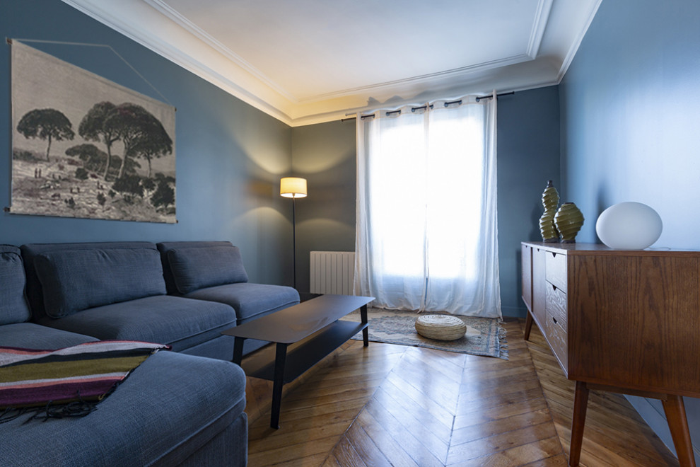 Réalisation d'un salon design avec un mur bleu et un sol en bois brun.