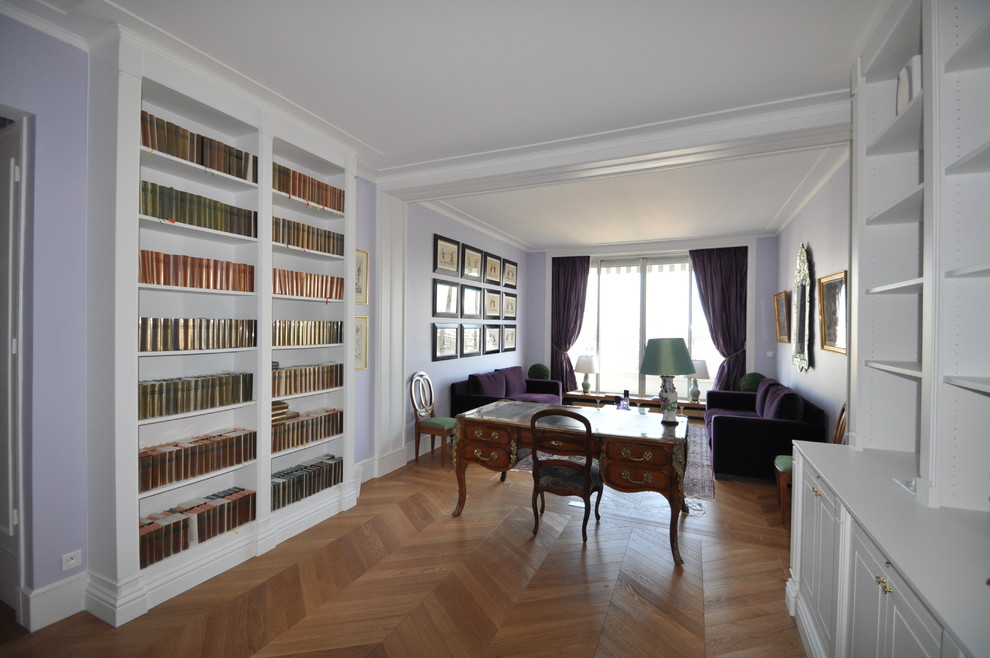 На фото: большая изолированная гостиная комната в стиле неоклассика (современная классика) с с книжными шкафами и полками, фиолетовыми стенами и коричневым полом с
