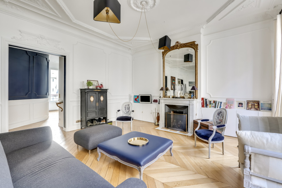 パリにあるお手頃価格の広いエクレクティックスタイルのおしゃれな応接間 (白い壁、淡色無垢フローリング、標準型暖炉、石材の暖炉まわり、内蔵型テレビ、ベージュの床) の写真