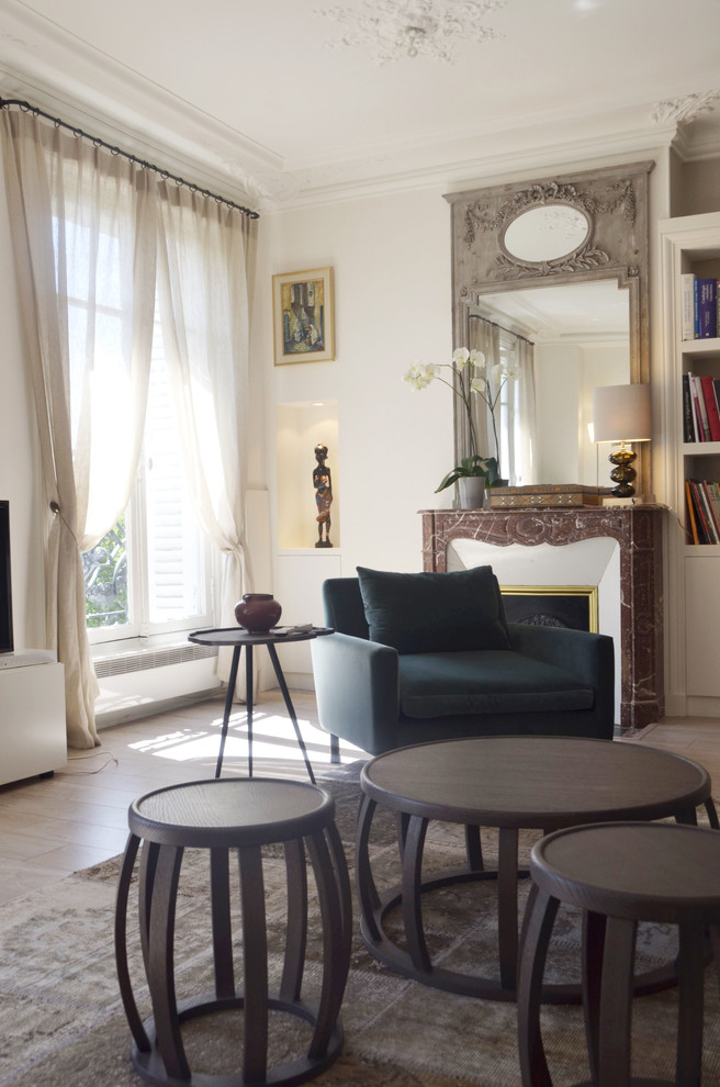 パリにあるラグジュアリーな広いコンテンポラリースタイルのおしゃれな独立型リビング (ライブラリー、白い壁、淡色無垢フローリング、標準型暖炉、石材の暖炉まわり、テレビなし) の写真