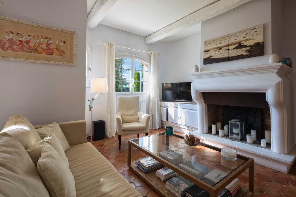 Cette image montre un salon traditionnel ouvert avec un mur gris, tomettes au sol, une cheminée standard et un téléviseur indépendant.