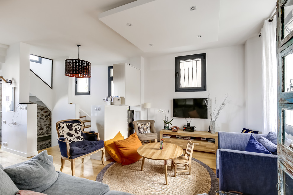 Стильный дизайн: открытая гостиная комната среднего размера в скандинавском стиле с белыми стенами, паркетным полом среднего тона, телевизором на стене, домашним баром и синим диваном без камина - последний тренд