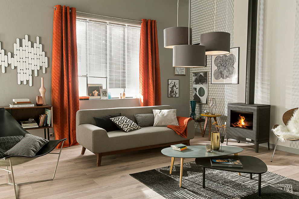 Medium sized contemporary living room in Lille with a reading nook, grey walls, light hardwood flooring, a wood burning stove, a metal fireplace surround and no tv.
