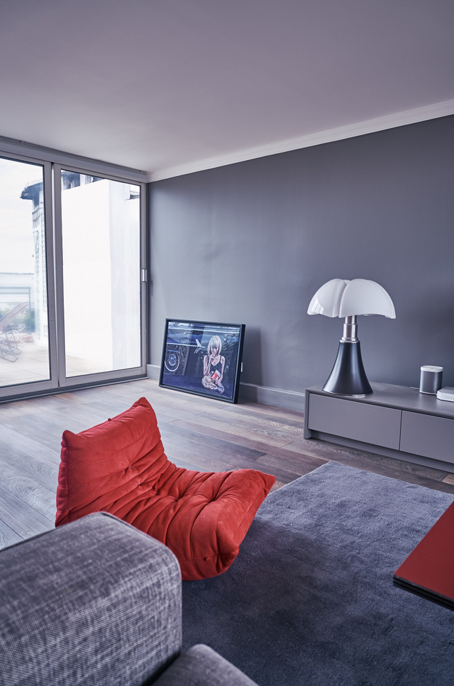 Idée de décoration pour un salon design de taille moyenne et ouvert avec un mur gris et parquet foncé.