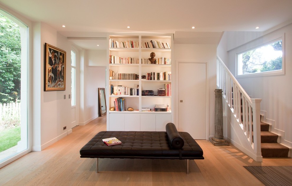 Ejemplo de biblioteca en casa abierta clásica renovada de tamaño medio sin chimenea y televisor con paredes blancas y suelo de madera en tonos medios