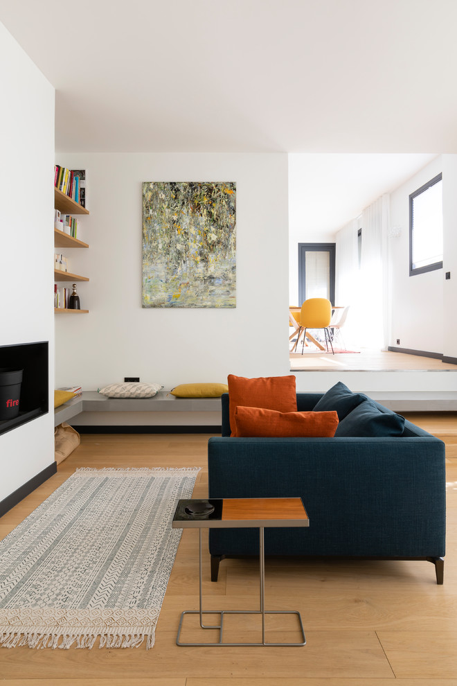 Mittelgroßes, Fernseherloses, Offenes Modernes Wohnzimmer mit weißer Wandfarbe, hellem Holzboden und Kamin in Paris