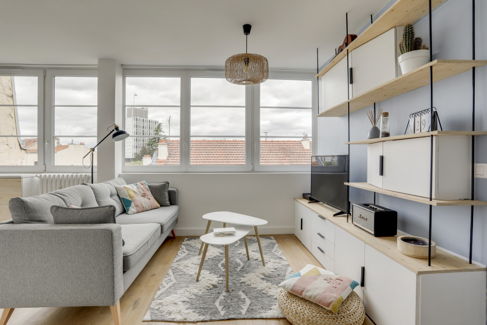 Пример оригинального дизайна: открытая гостиная комната среднего размера в скандинавском стиле с синими стенами, светлым паркетным полом, отдельно стоящим телевизором и бежевым полом без камина