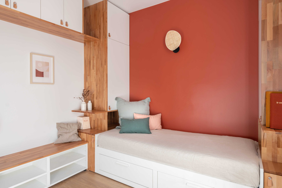 Modern inredning av ett litet separat vardagsrum, med röda väggar, ljust trägolv och en väggmonterad TV
