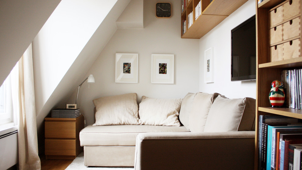 Cette image montre un salon design avec un mur blanc, un sol en bois brun, un téléviseur fixé au mur et un sol marron.