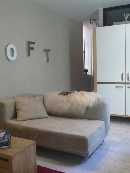 Cette image montre un petit salon design ouvert avec un mur gris et parquet clair.