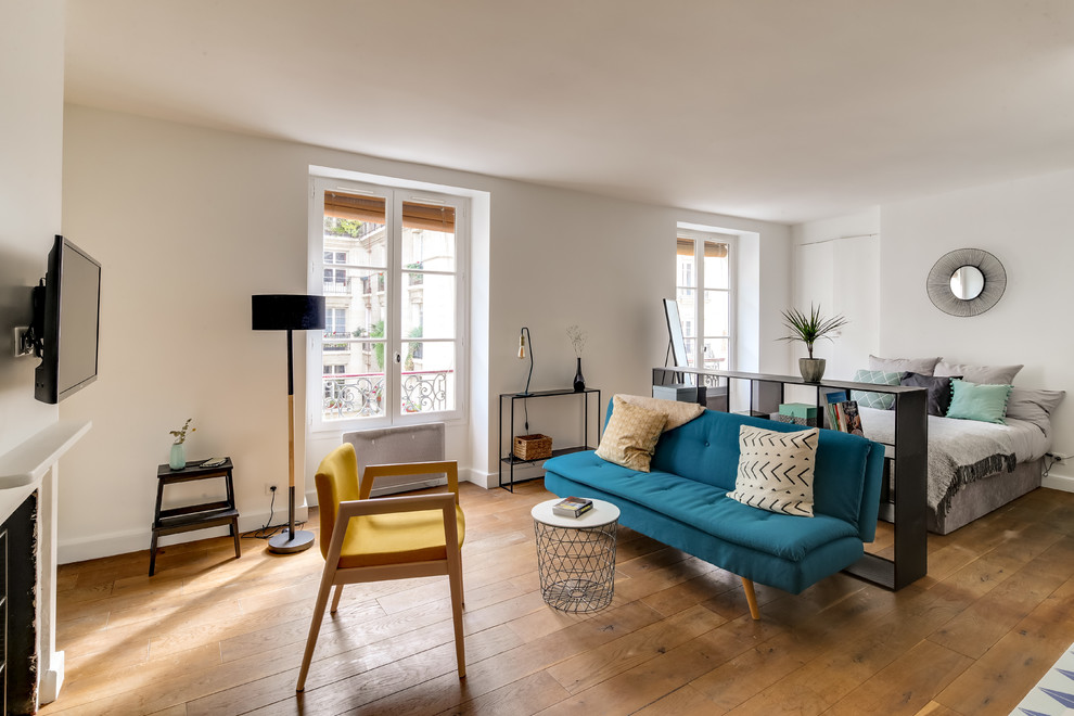 Immagine di un piccolo soggiorno minimalista aperto con pareti bianche, parquet chiaro, camino classico, TV a parete e pavimento marrone