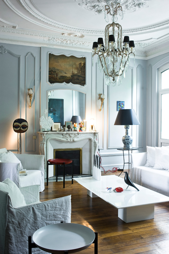 Living room - mid-sized eclectic formal and enclosed medium tone wood floor living room idea in Paris with a standard fireplace, white walls, a stone fireplace and no tv