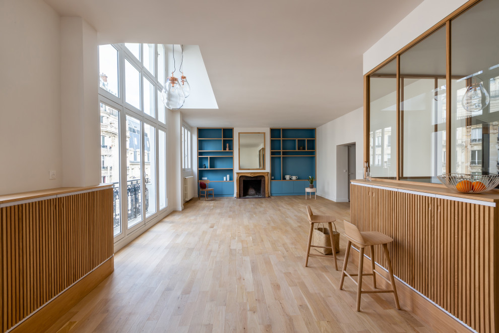 Großes, Fernseherloses, Offenes Modernes Wohnzimmer mit Hausbar, blauer Wandfarbe, hellem Holzboden, Kamin und Kaminumrandung aus Holz in Paris