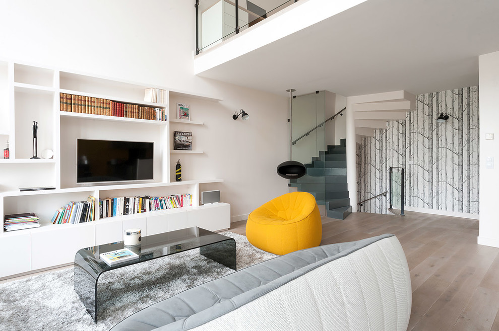 Medium sized scandinavian grey and yellow open plan living room in Paris with a reading nook, white walls, light hardwood flooring and a built-in media unit.