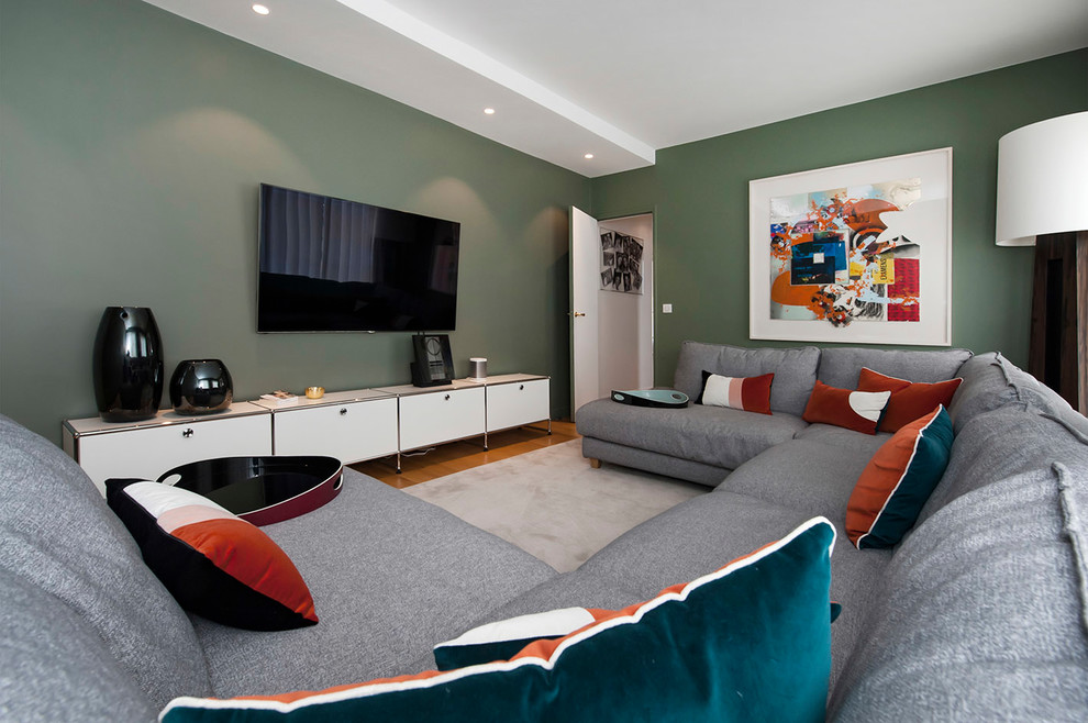 Ispirazione per un grande soggiorno design aperto con pareti verdi, TV a parete, libreria, parquet chiaro, nessun camino e pavimento marrone