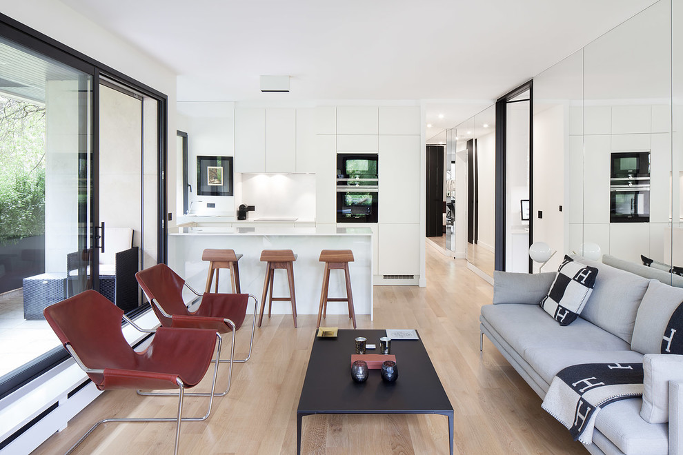 Ispirazione per un soggiorno design aperto con pareti bianche, pavimento in legno massello medio e pavimento beige