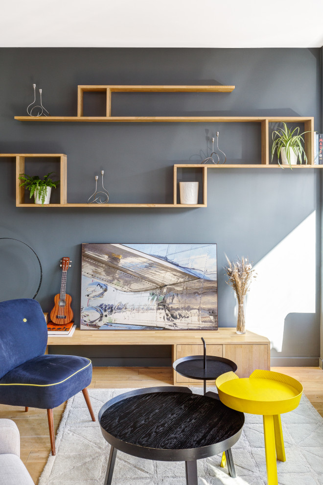 Diseño de salón abierto moderno grande sin chimenea con paredes grises, suelo de madera clara, televisor independiente y suelo beige