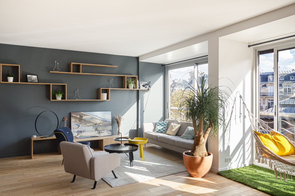 Diseño de salón abierto minimalista grande sin chimenea con paredes grises, suelo de madera clara, televisor independiente y suelo beige