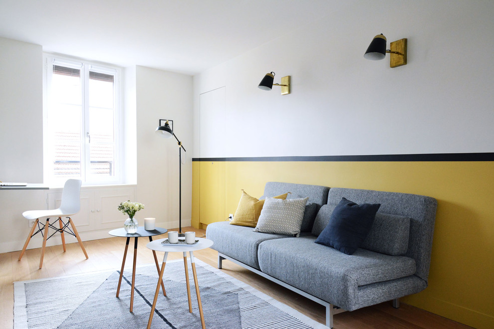 Cette photo montre un salon scandinave avec parquet clair, aucune cheminée, un sol marron, un mur jaune et éclairage.