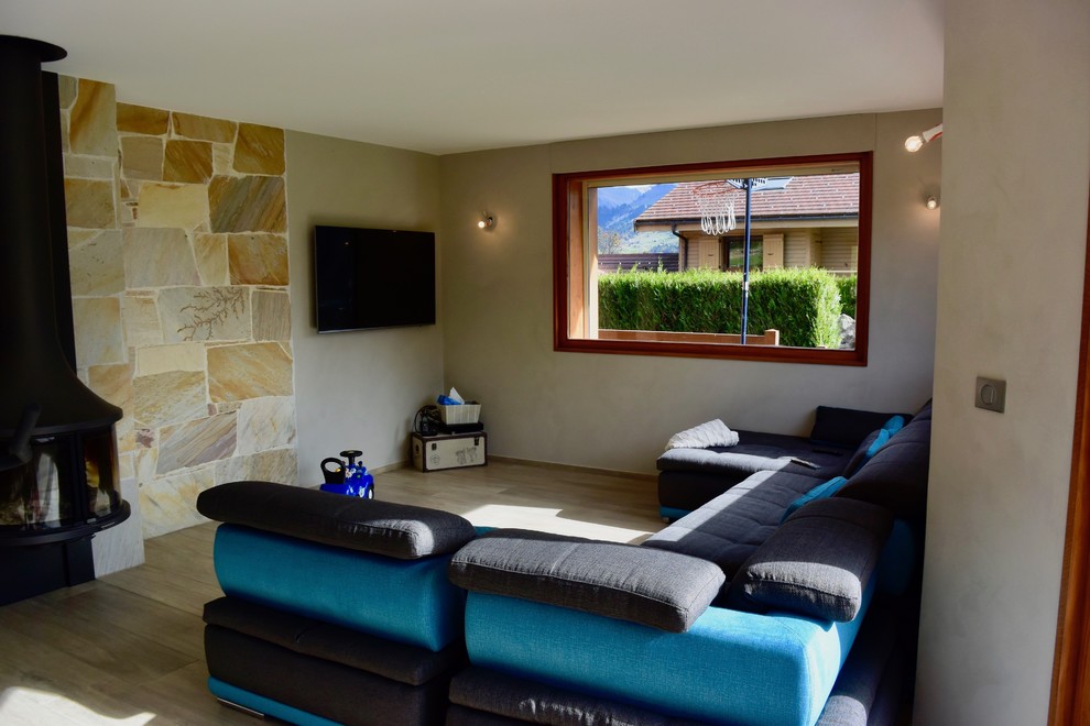 На фото: большая открытая гостиная комната в скандинавском стиле с серыми стенами, полом из керамической плитки, подвесным камином, фасадом камина из металла, телевизором на стене и бежевым полом с