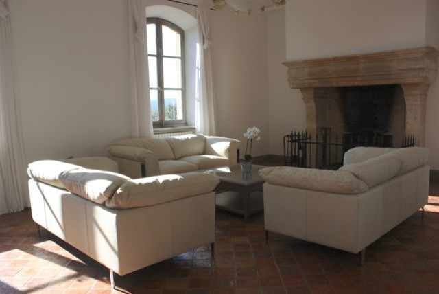 Cette photo montre un grand salon nature ouvert avec un mur beige, tomettes au sol, une cheminée standard, un manteau de cheminée en pierre, aucun téléviseur et un sol rouge.
