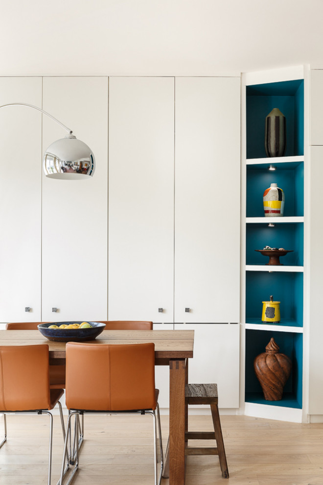Пример оригинального дизайна: изолированная гостиная комната среднего размера в современном стиле с с книжными шкафами и полками, белыми стенами, светлым паркетным полом, отдельно стоящим телевизором и коричневым полом без камина