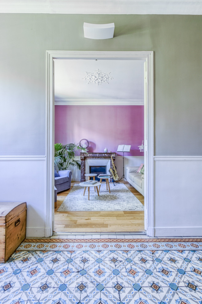 Mittelgroßes, Fernseherloses Wohnzimmer mit lila Wandfarbe, hellem Holzboden, Kamin und Kaminumrandung aus Stein in Paris