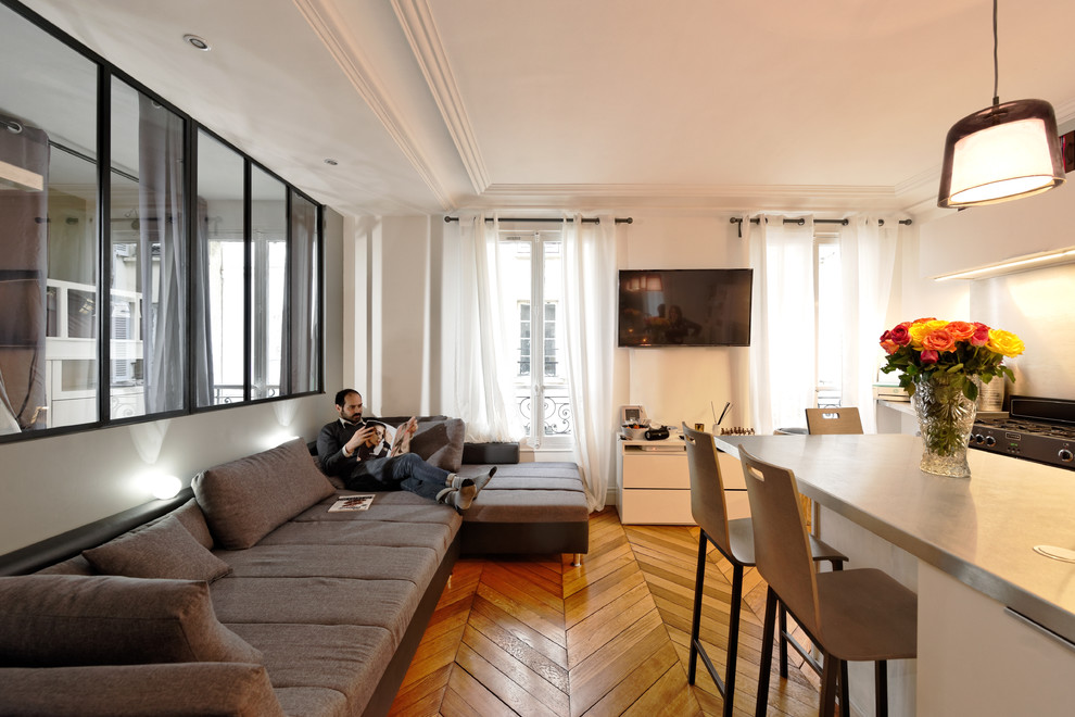 Ejemplo de salón contemporáneo con paredes blancas, suelo de madera en tonos medios, televisor colgado en la pared y suelo marrón