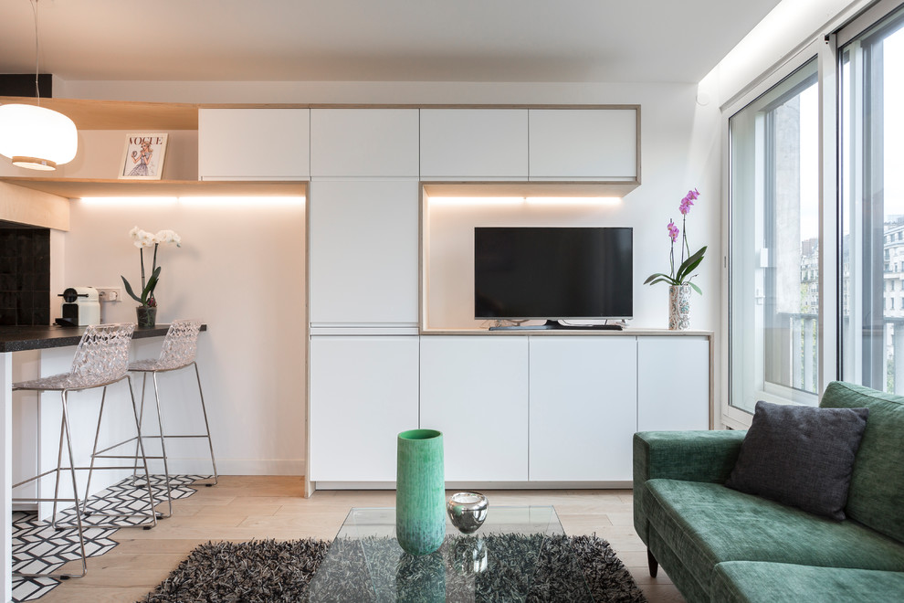 Example of a small danish open concept light wood floor living room design in Paris with green walls