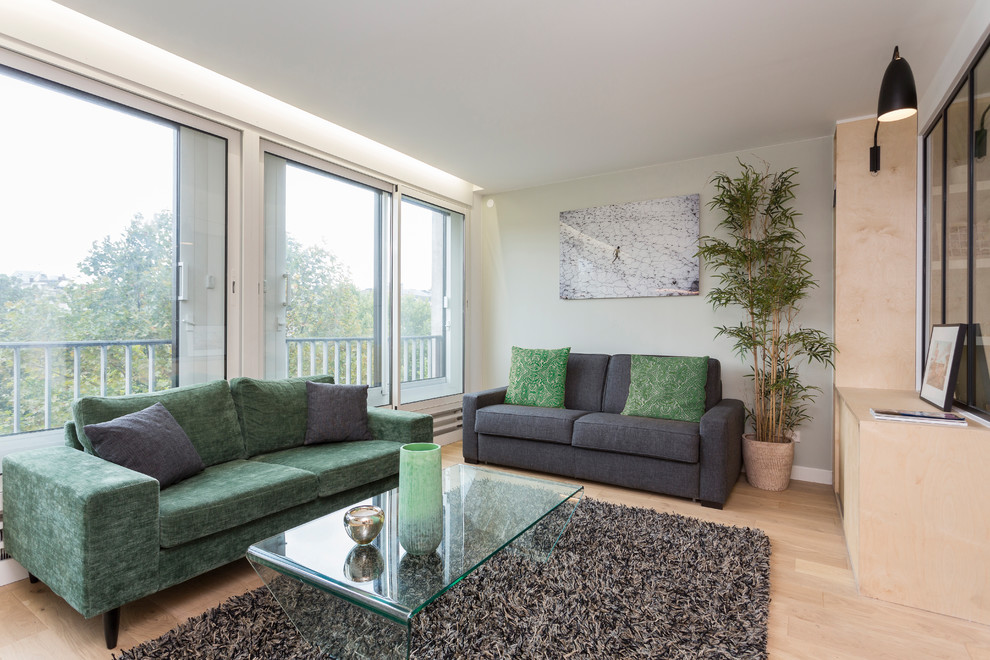 Example of a small danish open concept light wood floor living room design in Paris with green walls