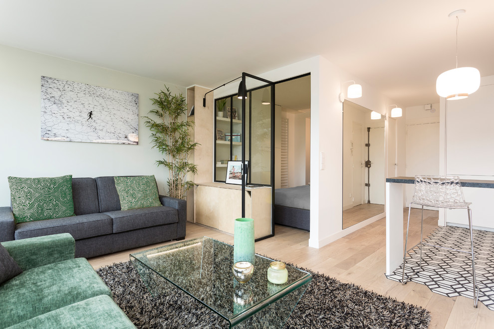 На фото: маленькая открытая гостиная комната в скандинавском стиле с зелеными стенами, светлым паркетным полом, отдельно стоящим телевизором и коричневым полом для на участке и в саду